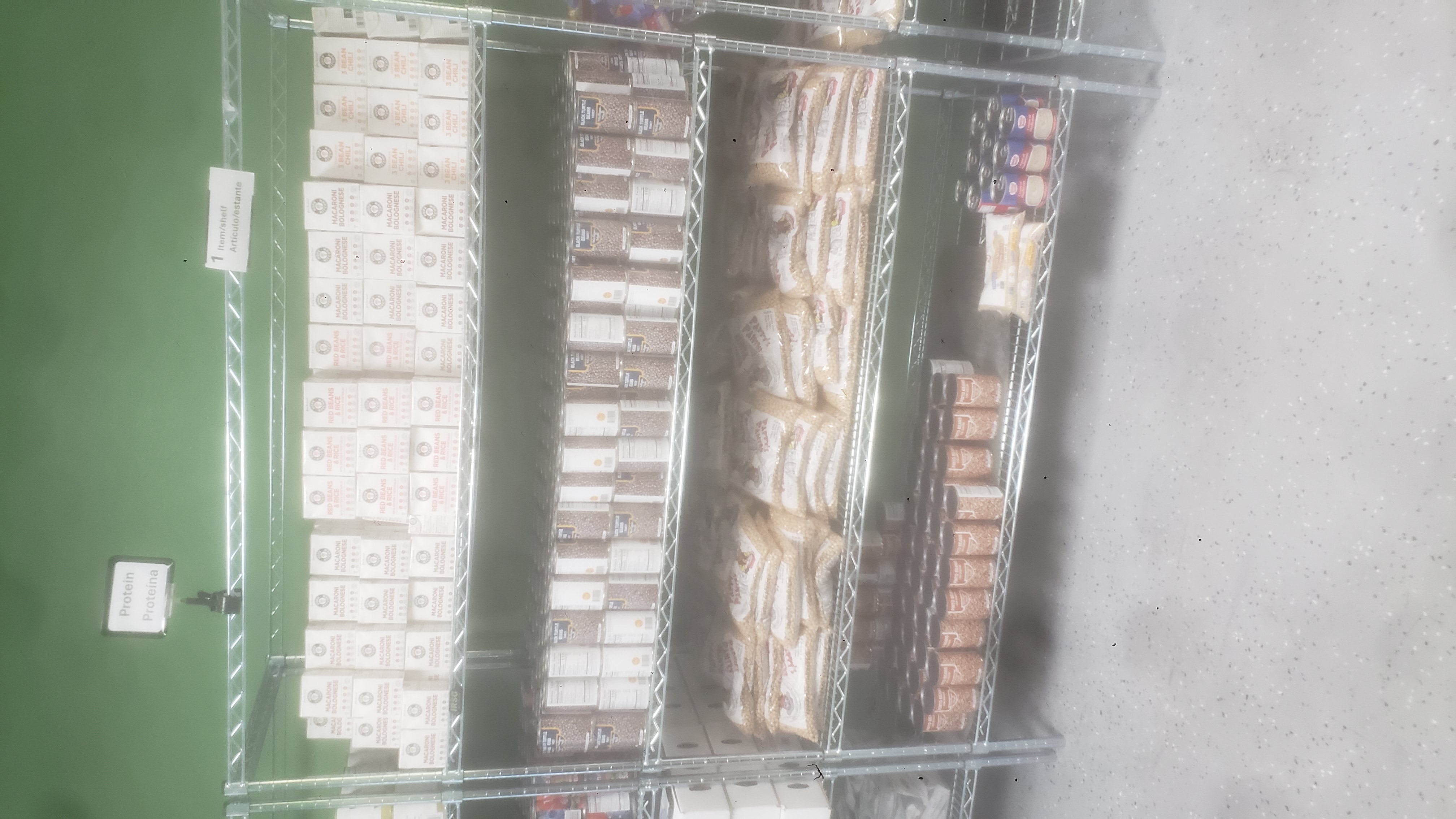 Canned pinto beans, bags of chickpeas, canned cream of mushroom soups, bags of brown rice, canned black turtle beans, and ready-to-eat meals on a four tier shelf.
